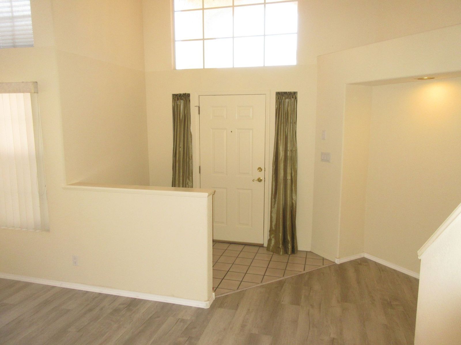 Entryway with a white door, sidelights, and tiled floor, with light wood-look flooring and cream-colored walls.