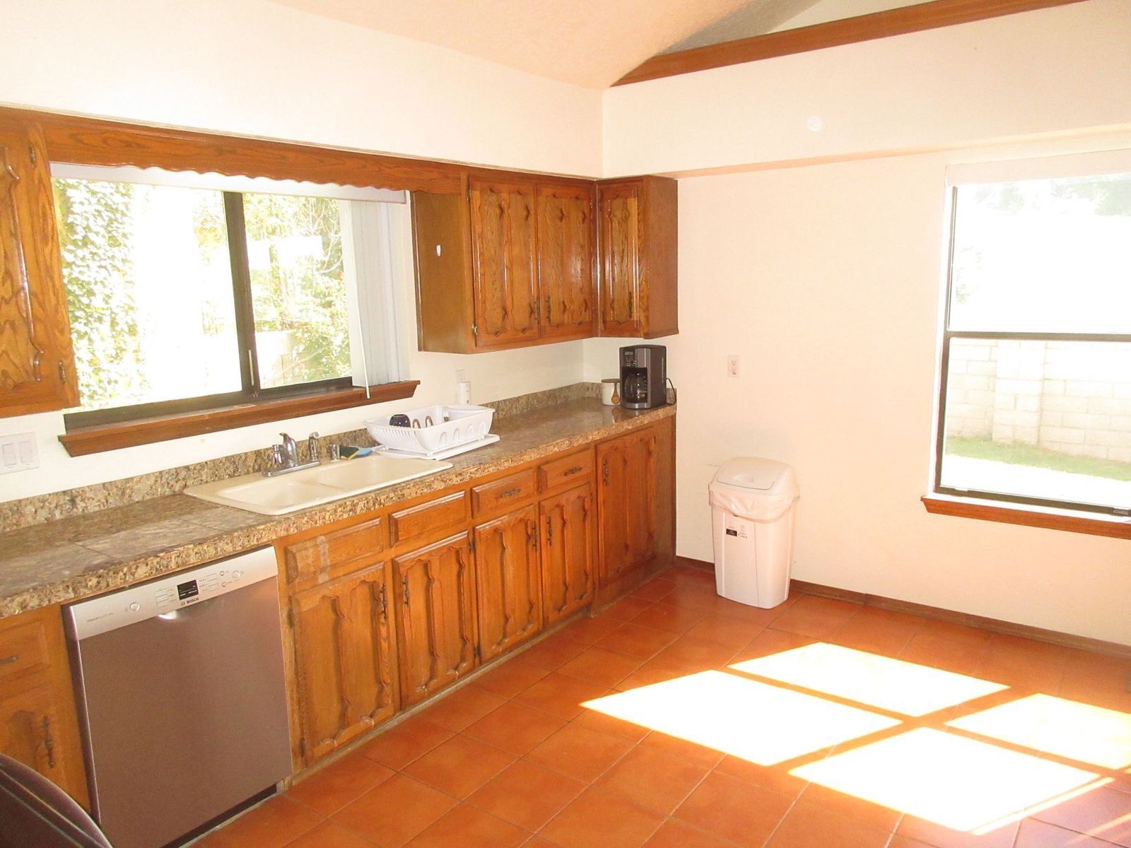 Kitchen with wood cabinets, tan countertop, stainless steel appliances, and tile floor.