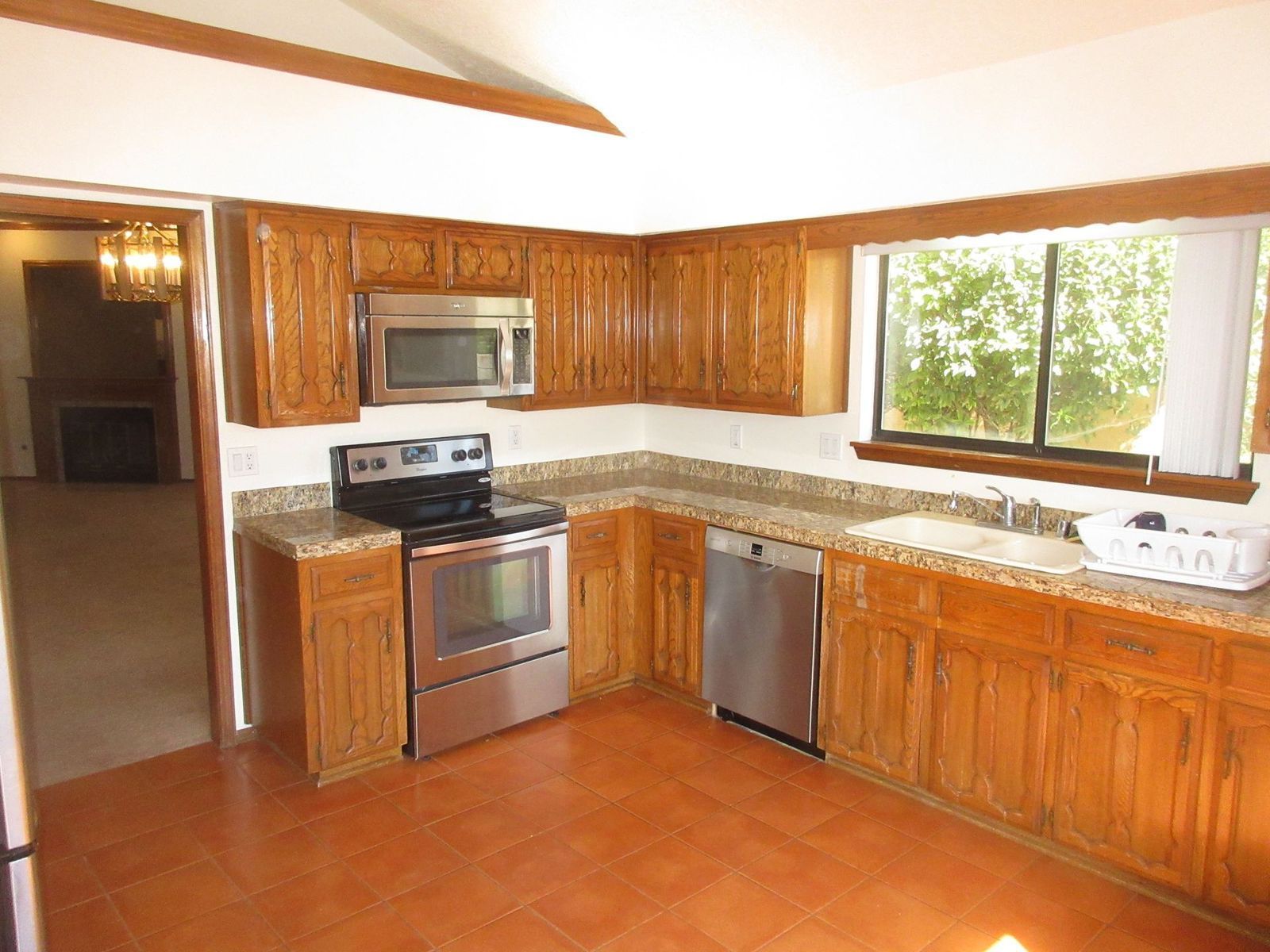Kitchen with wood cabinets, stainless steel appliances, and a window over the sink.