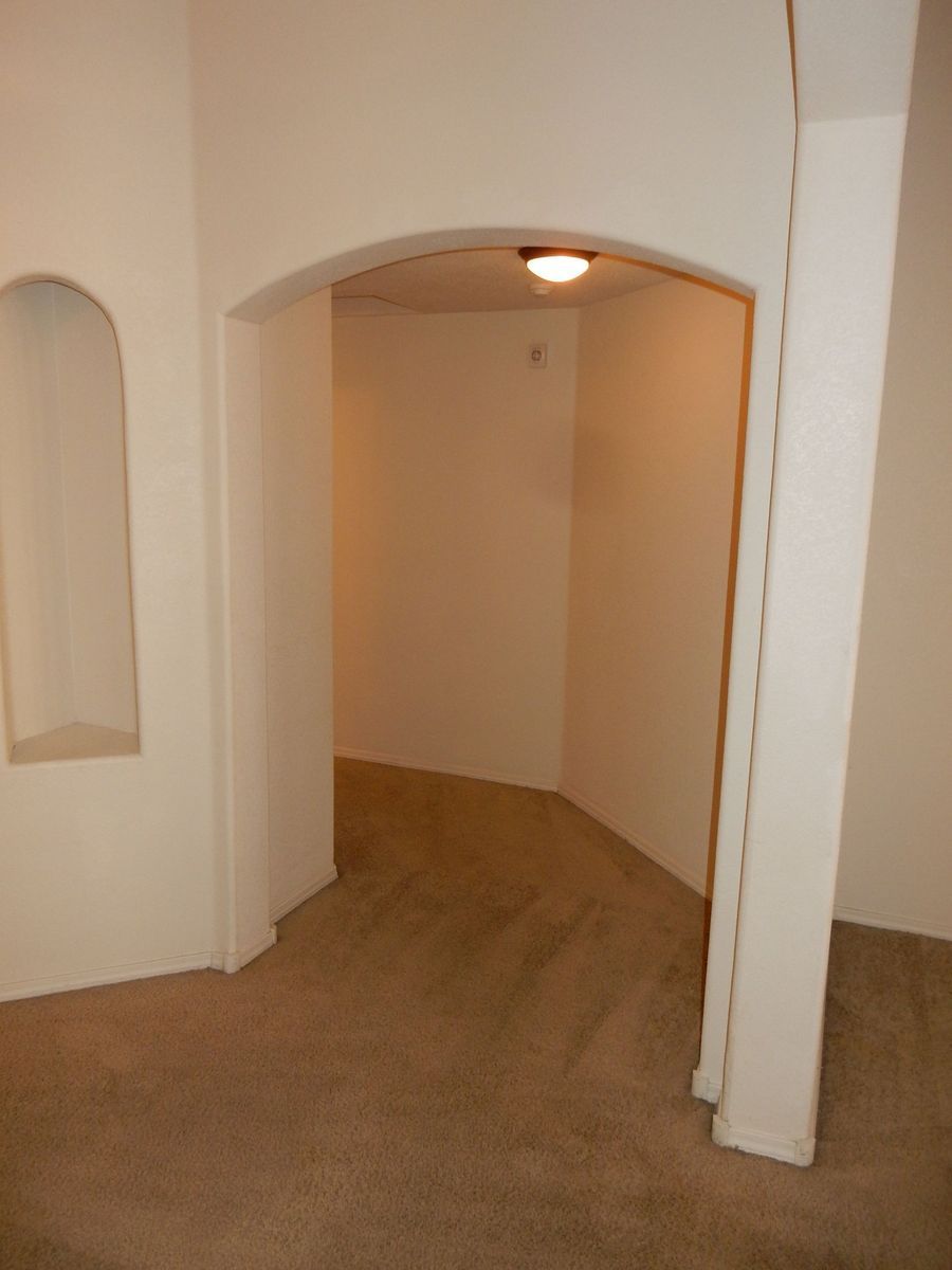 Interior doorway with arched opening, leading to a hallway. Cream-colored walls, beige carpet.