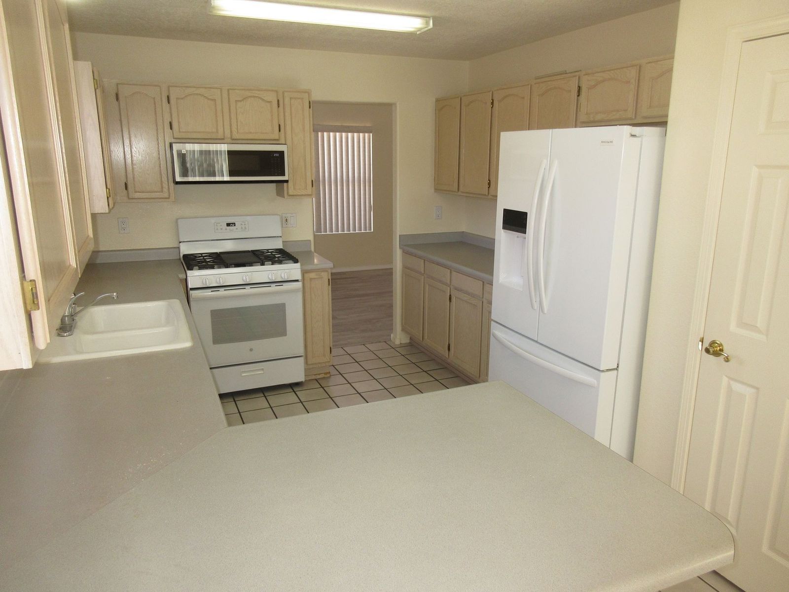 Kitchen with light-colored cabinets, white appliances, and a gray countertop.