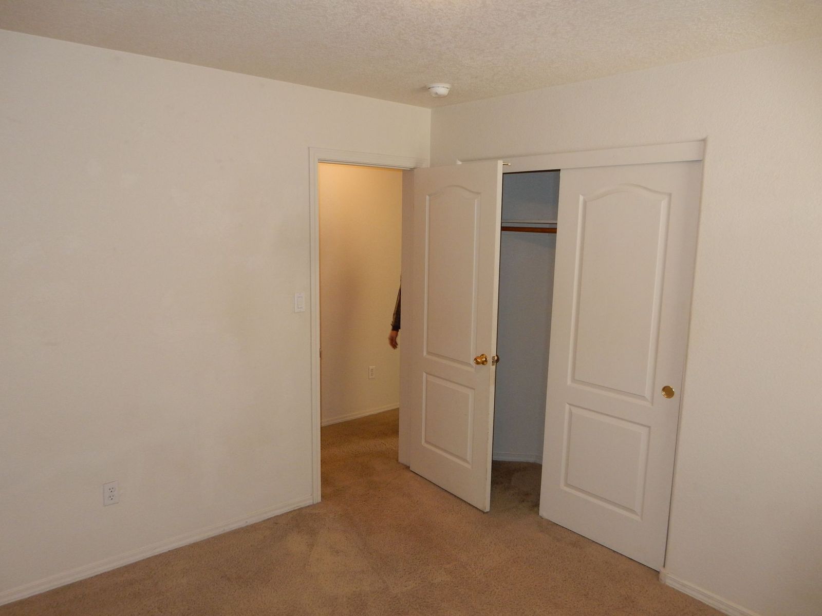 Empty room with white walls, carpet, and sliding closet doors. Another doorway is visible.