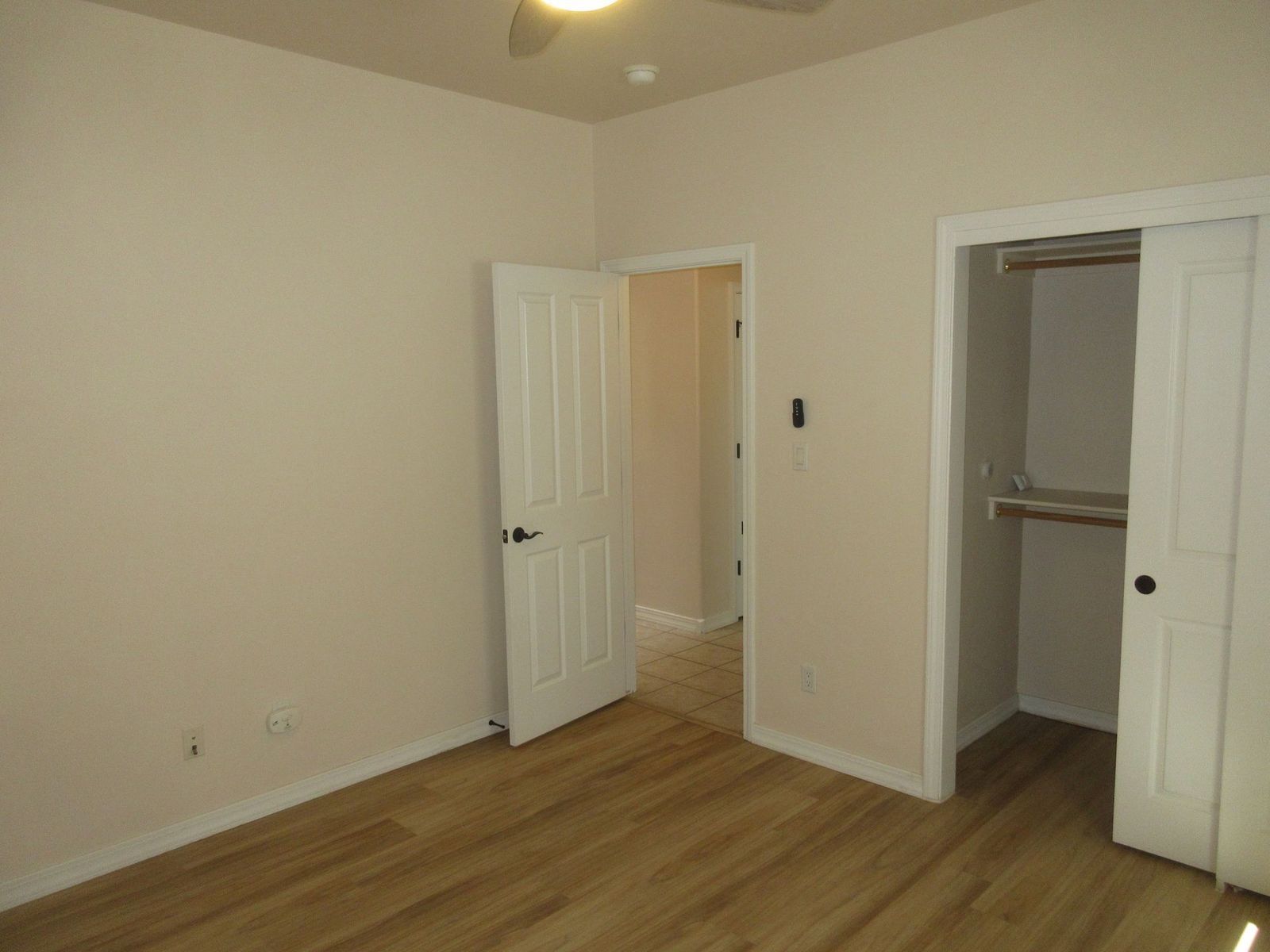 Empty bedroom with wood floors, closet, and open doorways.