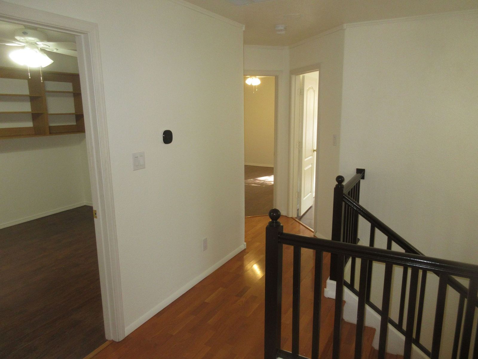 Hallway with wood floors, doors, and a staircase.
