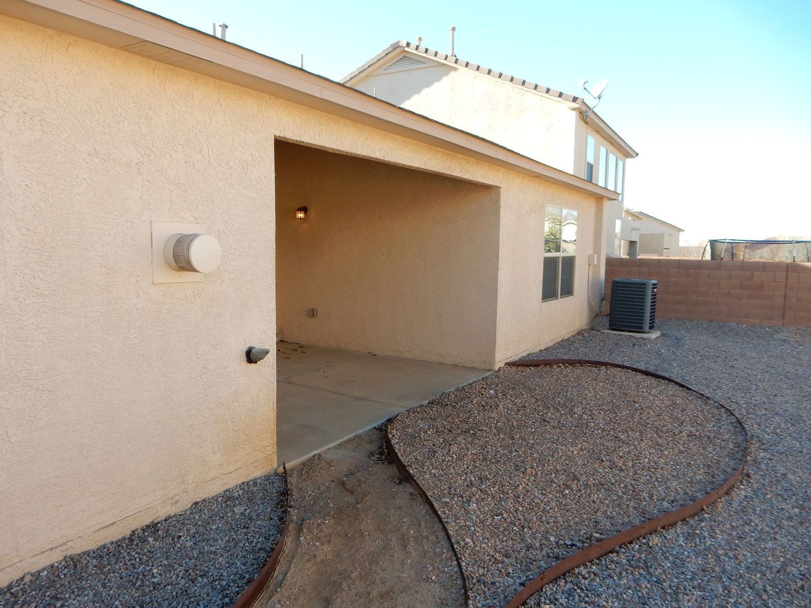 Covered patio with a gravel path, a concrete patio, and an air conditioning unit.