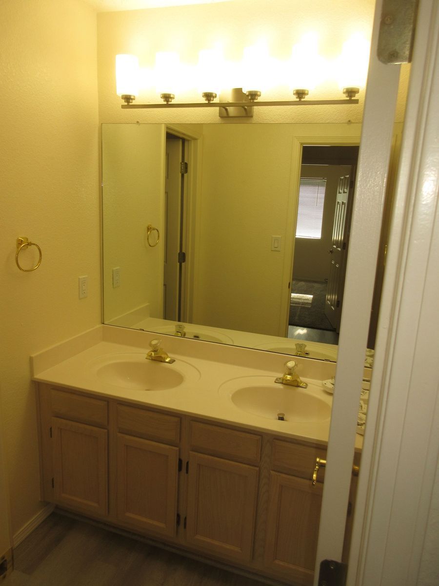 Bathroom with double sinks, large mirror, and overhead lighting. Beige vanity and walls.