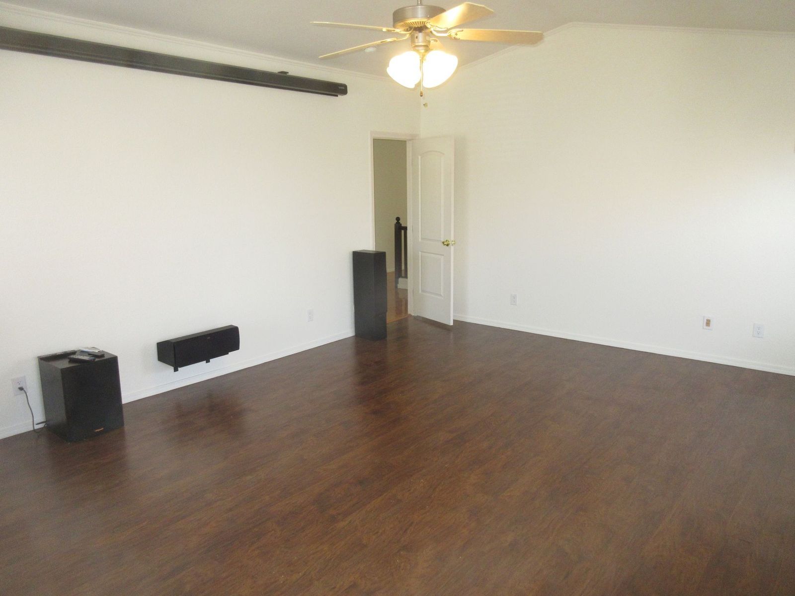 Empty room with dark wood floor, white walls, and a ceiling fan.