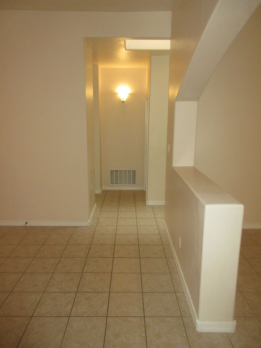 Interior hallway with beige tile floor, off-white walls, and recessed lighting.