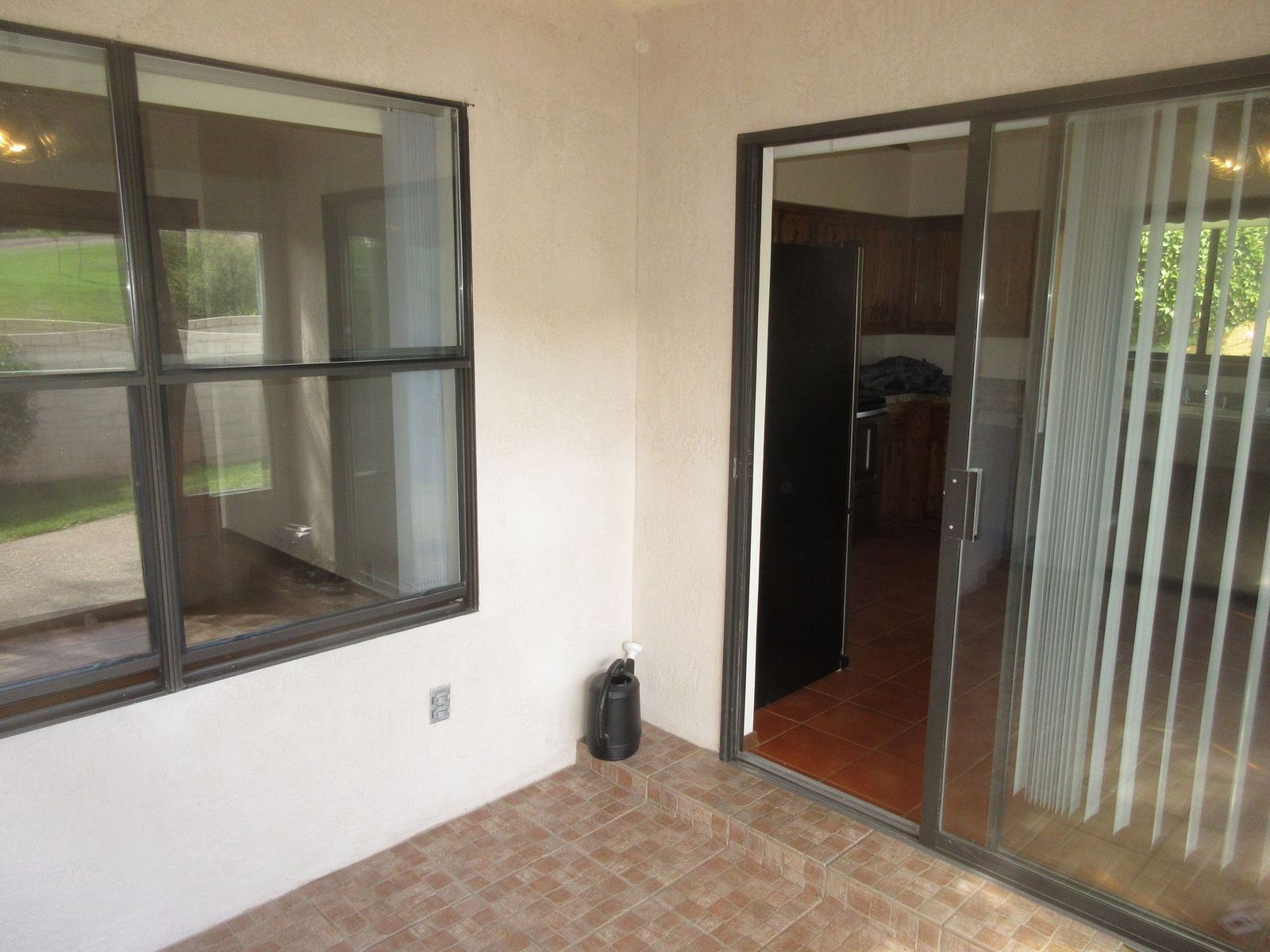 Enclosed patio with tile floor, windows, and sliding glass door leading to a kitchen.