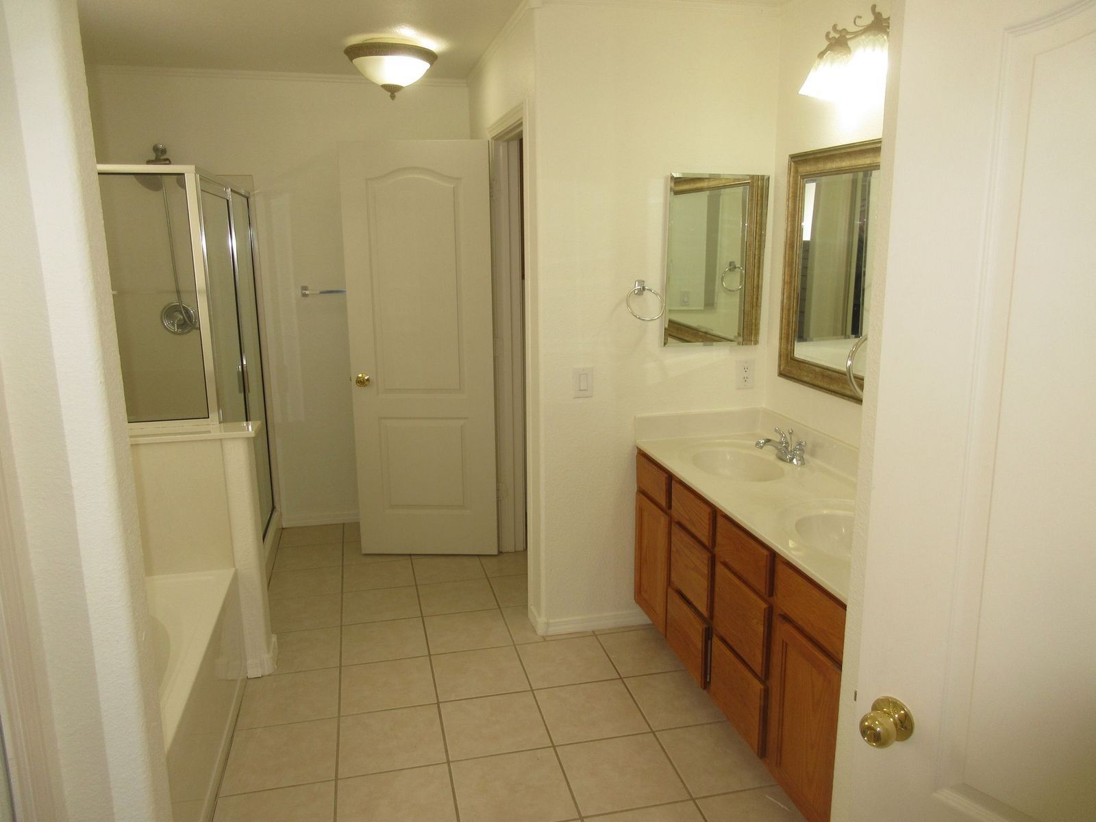 Bathroom with vanity, mirror, shower, and closed door; neutral colors.