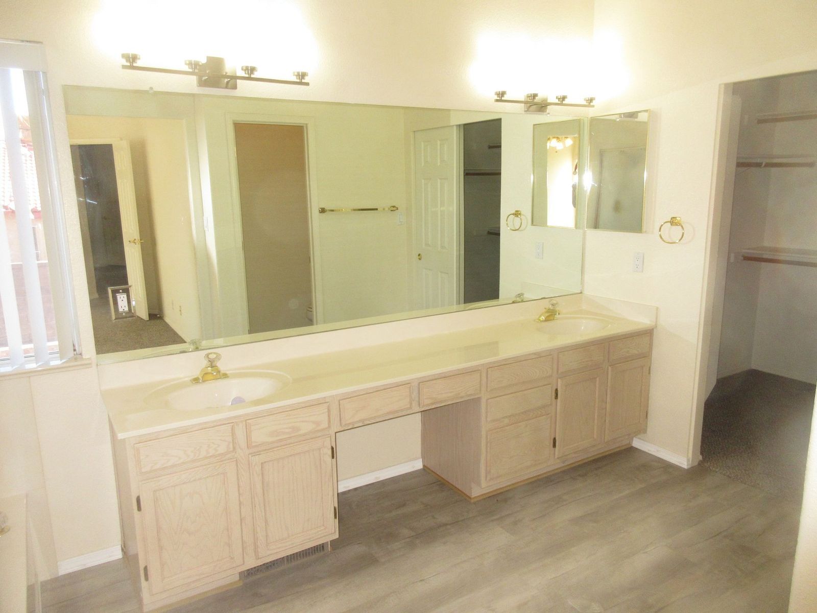 Bathroom with double vanity, large mirror, two sinks, and a walk-in closet.