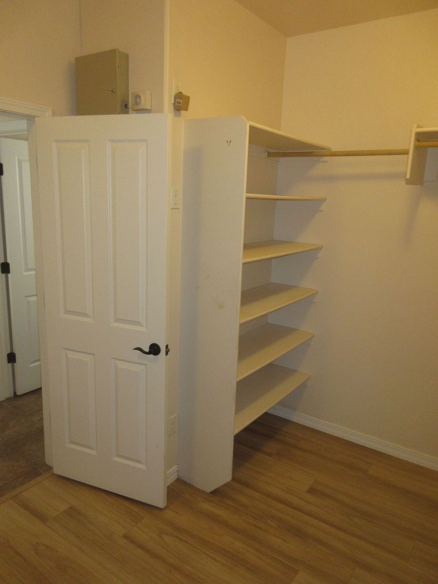 White closet interior with shelves, a clothing rod, and a partially open door.