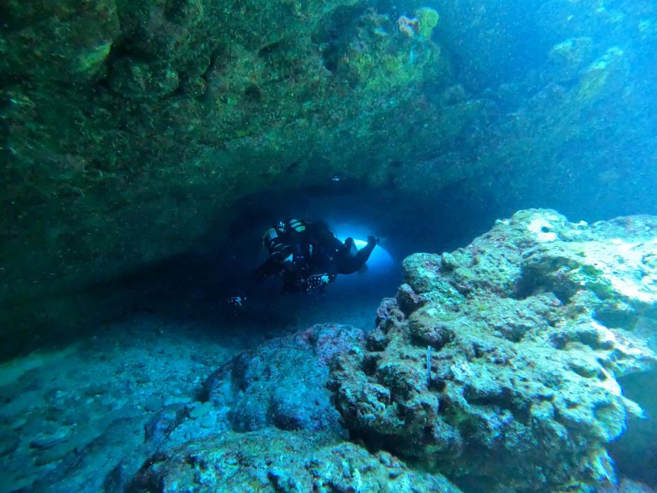 A scuba diver is entering a cave in the ocean.