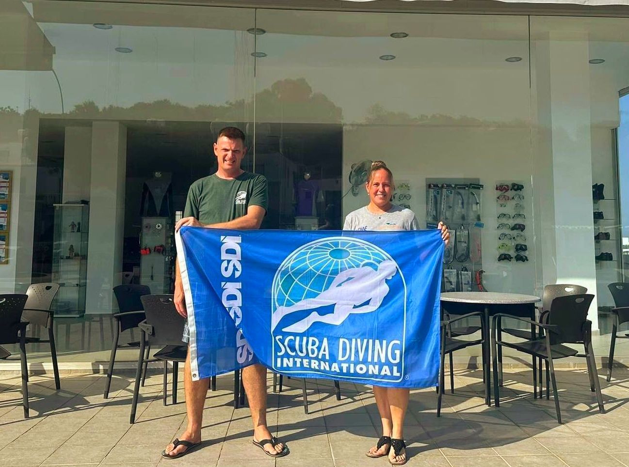 Two people are holding a blue flag that says scuba diving international.