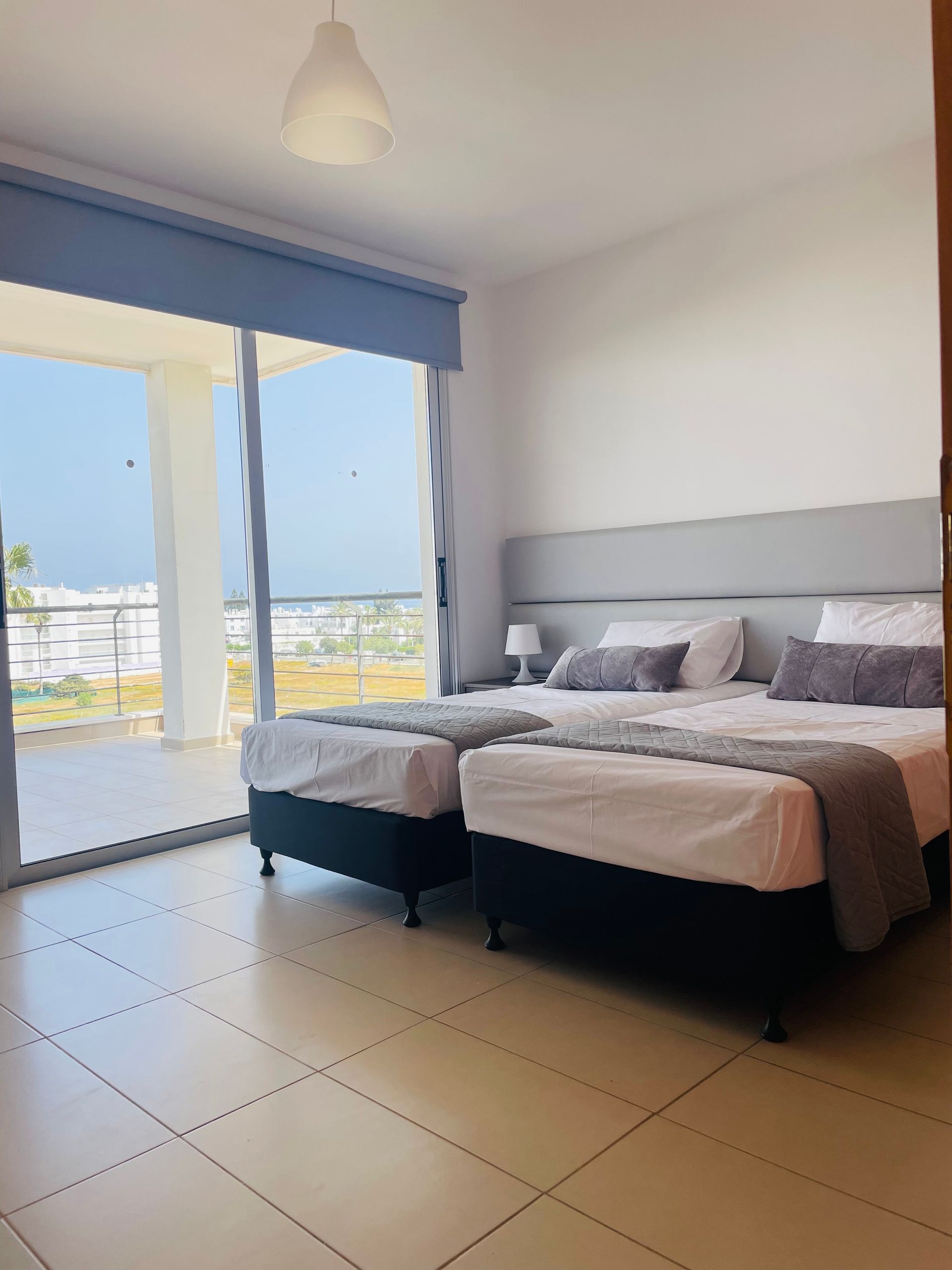 A hotel room with two beds and a sliding glass door.