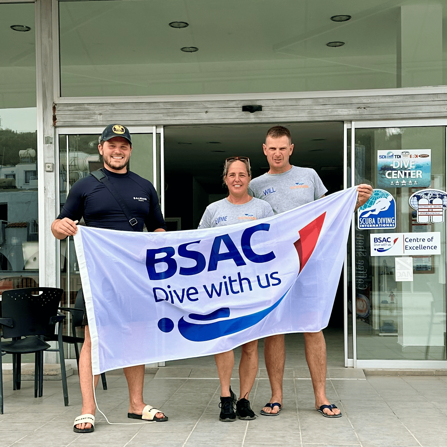 A group of people holding a bsac dive with us flag