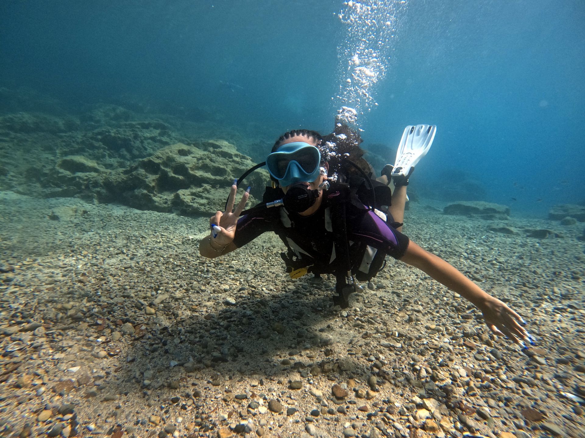 A scuba diver is giving a peace sign while swimming in the ocean.