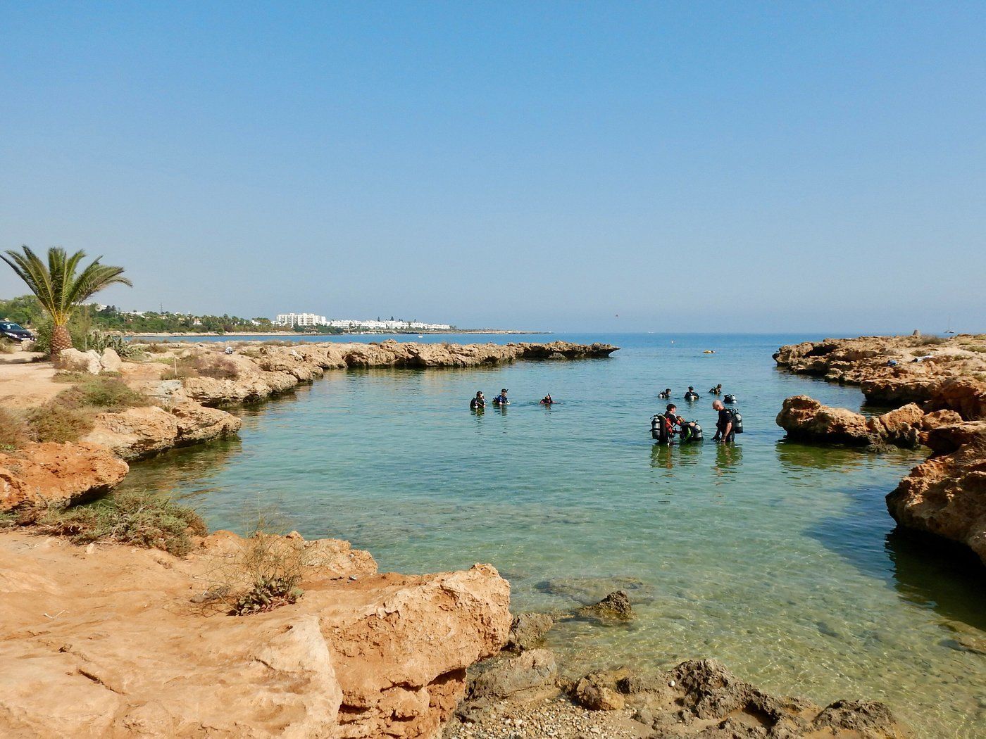 A group of people are swimming in a body of water surrounded by rocks.