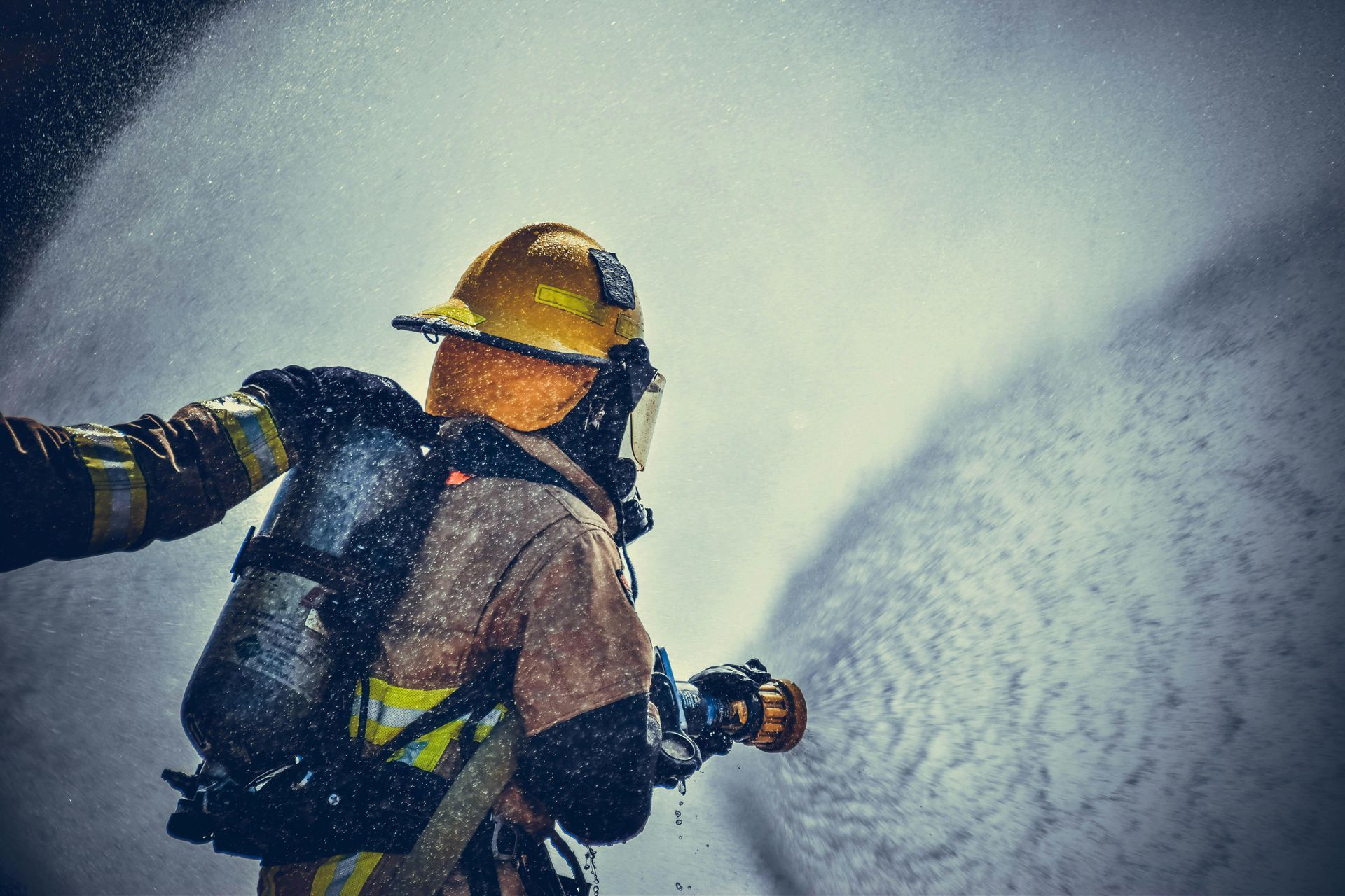 A fireman is spraying water from a hose at a fire.