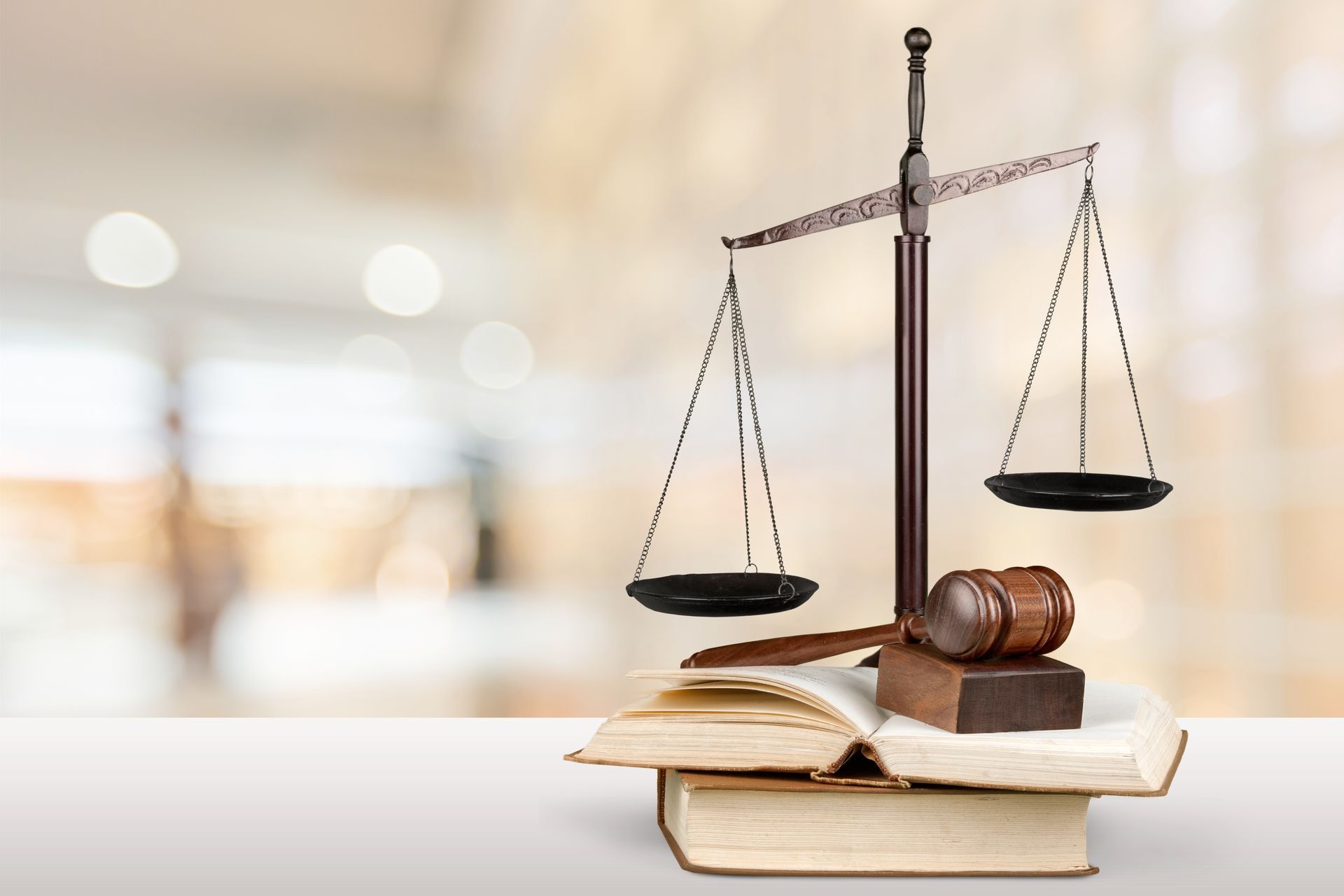 Scales of justice atop books with a gavel, against a blurred background.