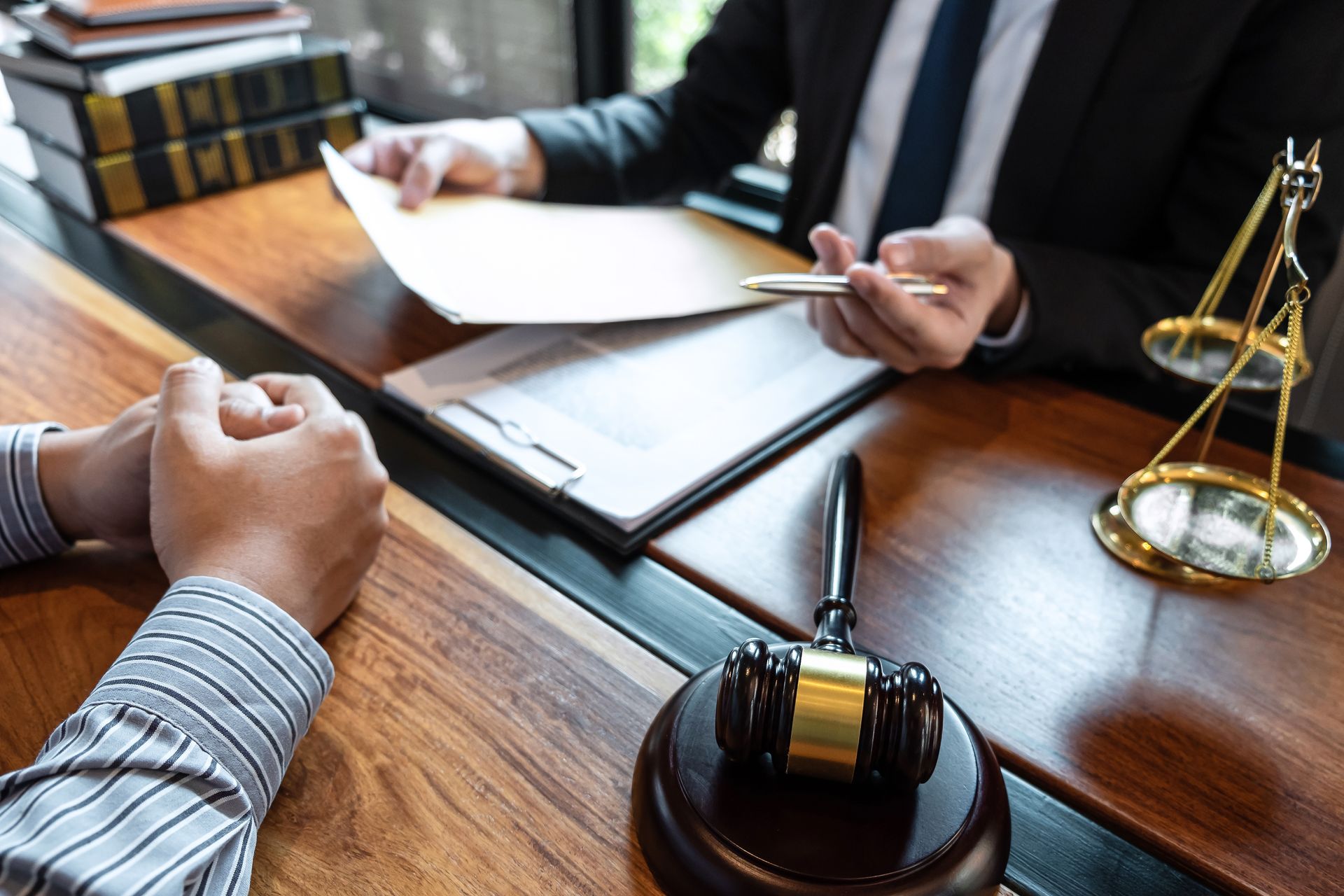Defense attorney reviewing legal documents with a client near a gavel.