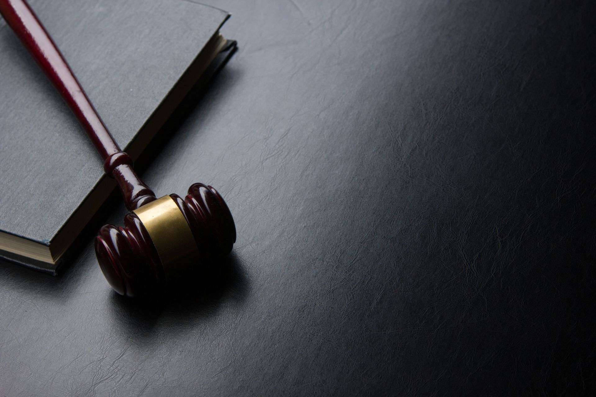Gavel and law book on a dark surface, symbolizing justice or legal proceedings.