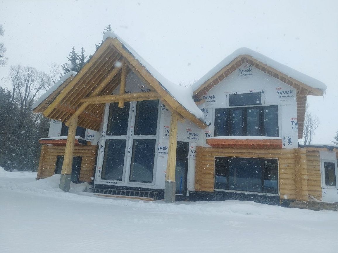 A house is being built in the snow and is covered in snow.