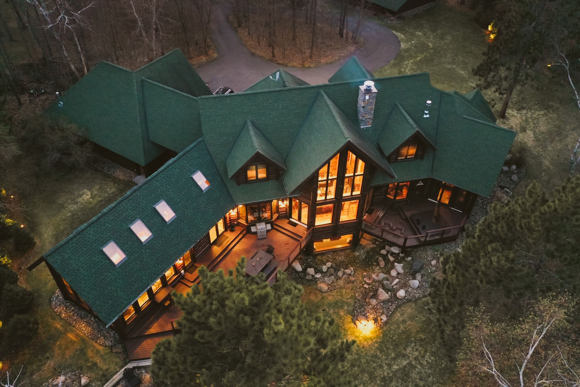 An aerial view of a large house in the middle of a forest at night.