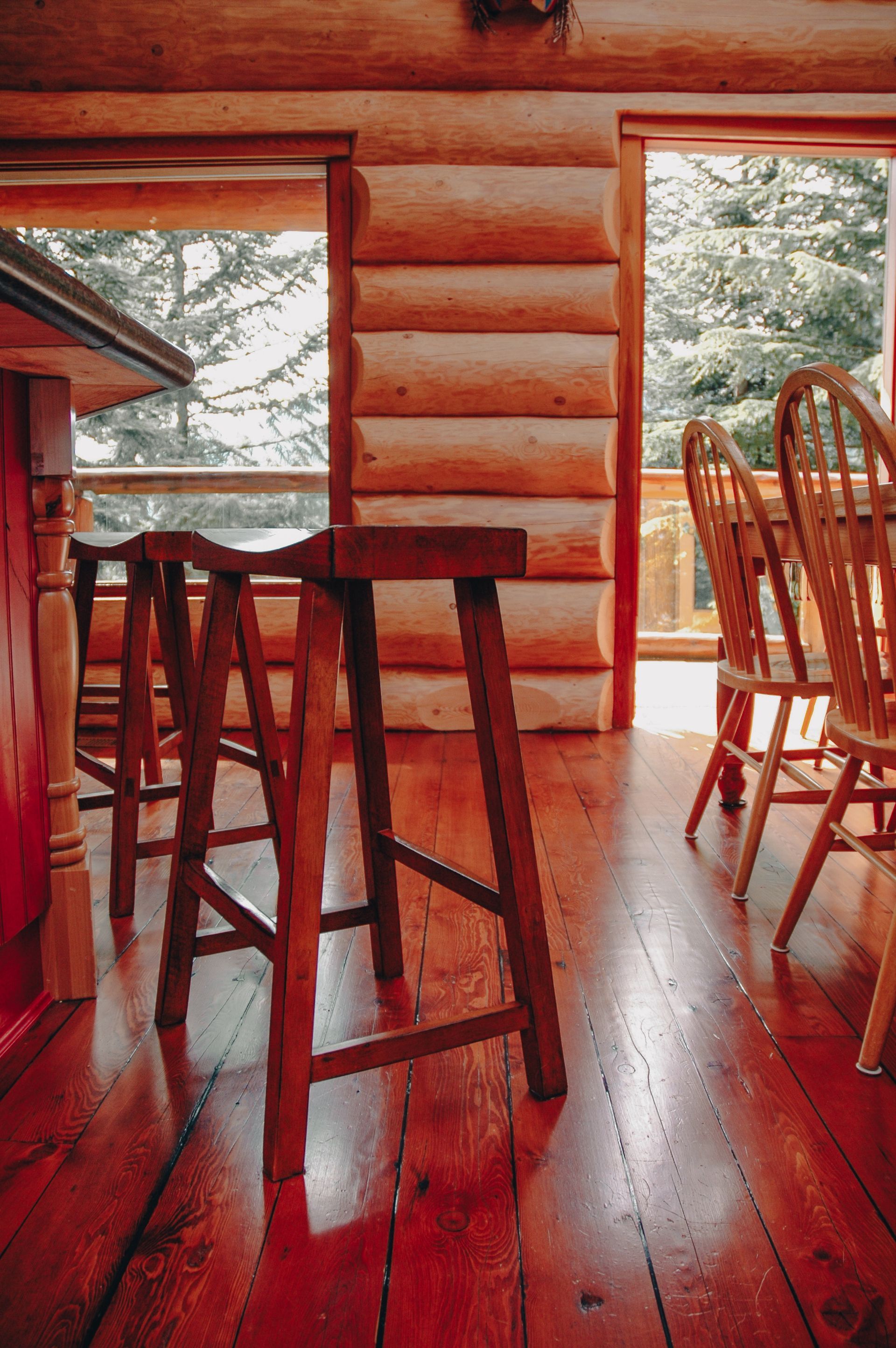 Two wooden stools are sitting on a wooden floor in a cabin.