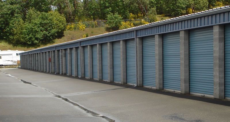 A row of blue garage doors are lined up in a parking lot.