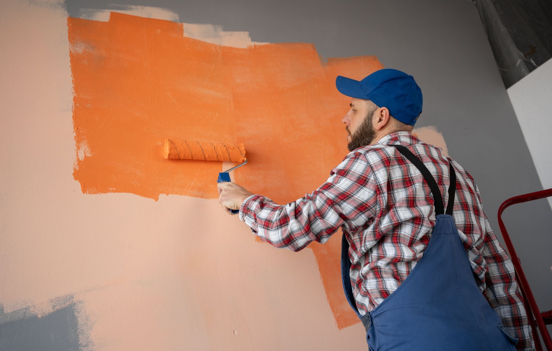 A man is painting a wall with a paint roller.