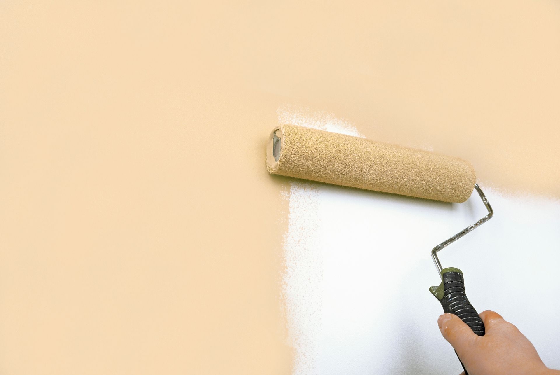 A person is painting a wall with a paint roller.