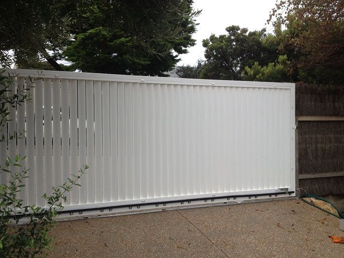 A white fence with a wooden fence behind it