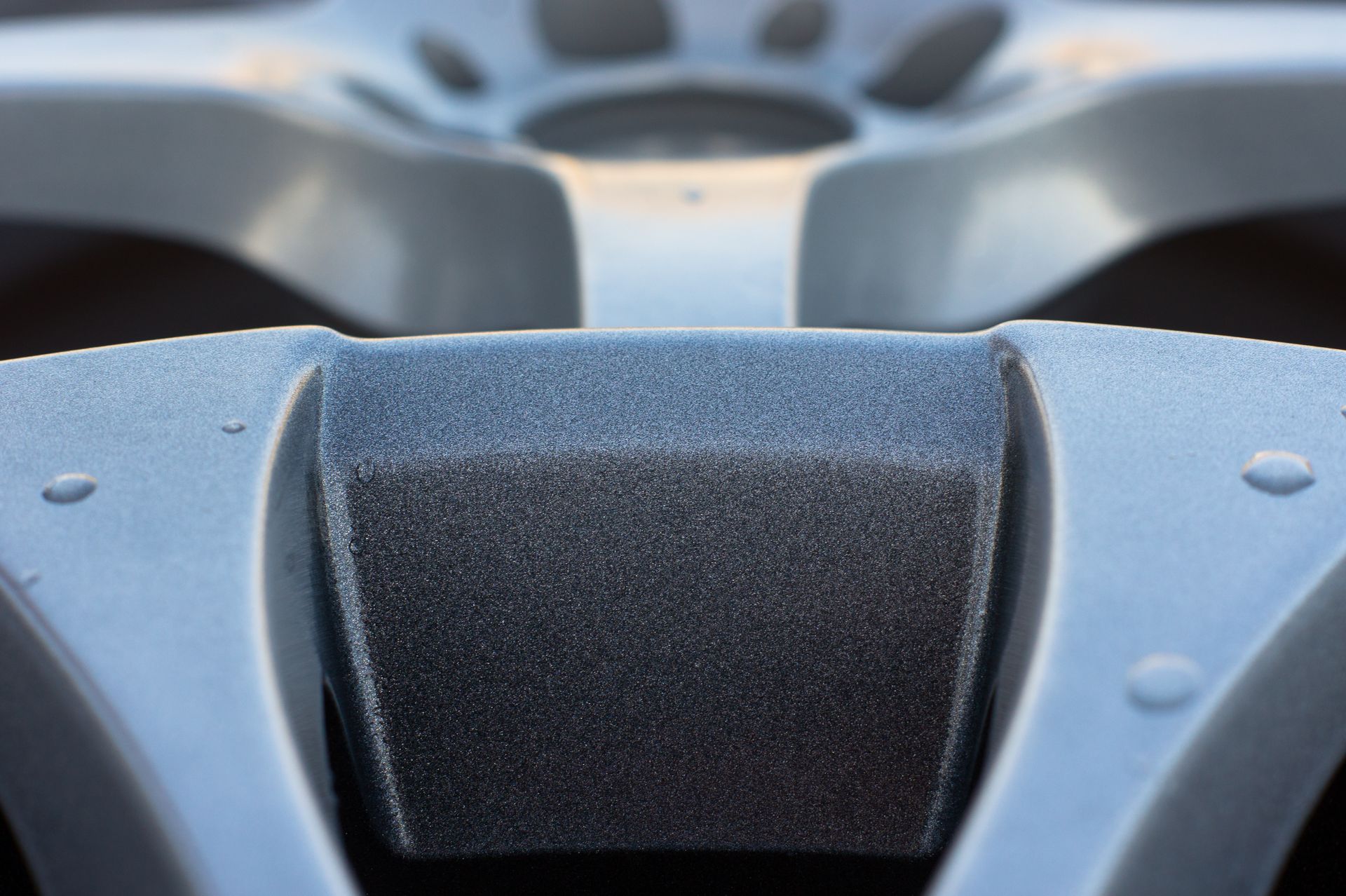 Close-up of a gray car wheel hub with a textured, rectangular center.