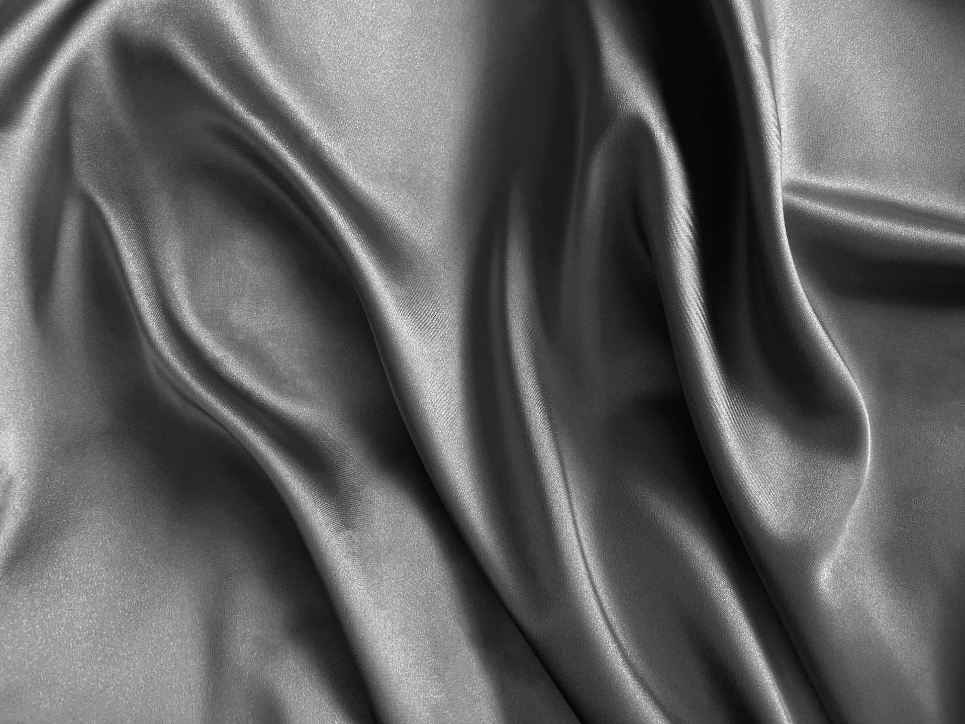 Gray, flowing satin fabric with highlights and shadows, tightly bunched with graceful folds.