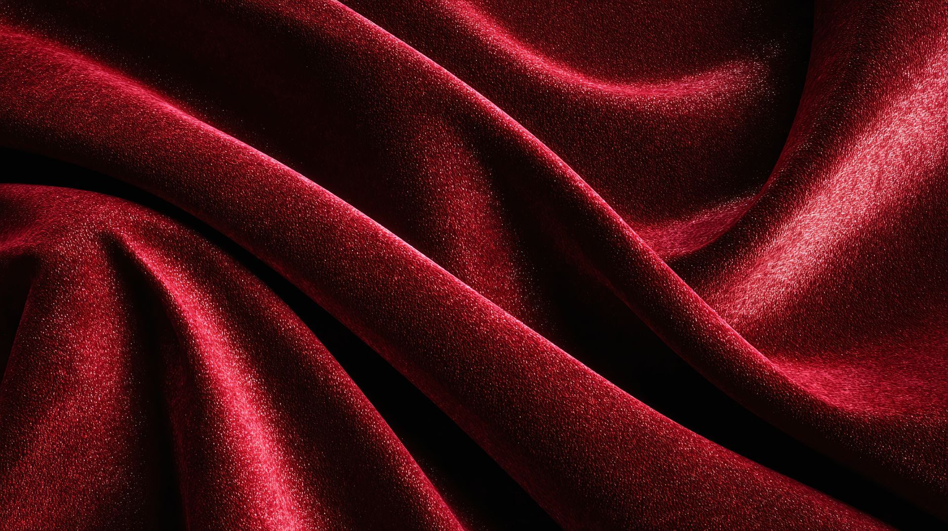 Close-up of draped, deep red velvet fabric with a shimmering texture.
