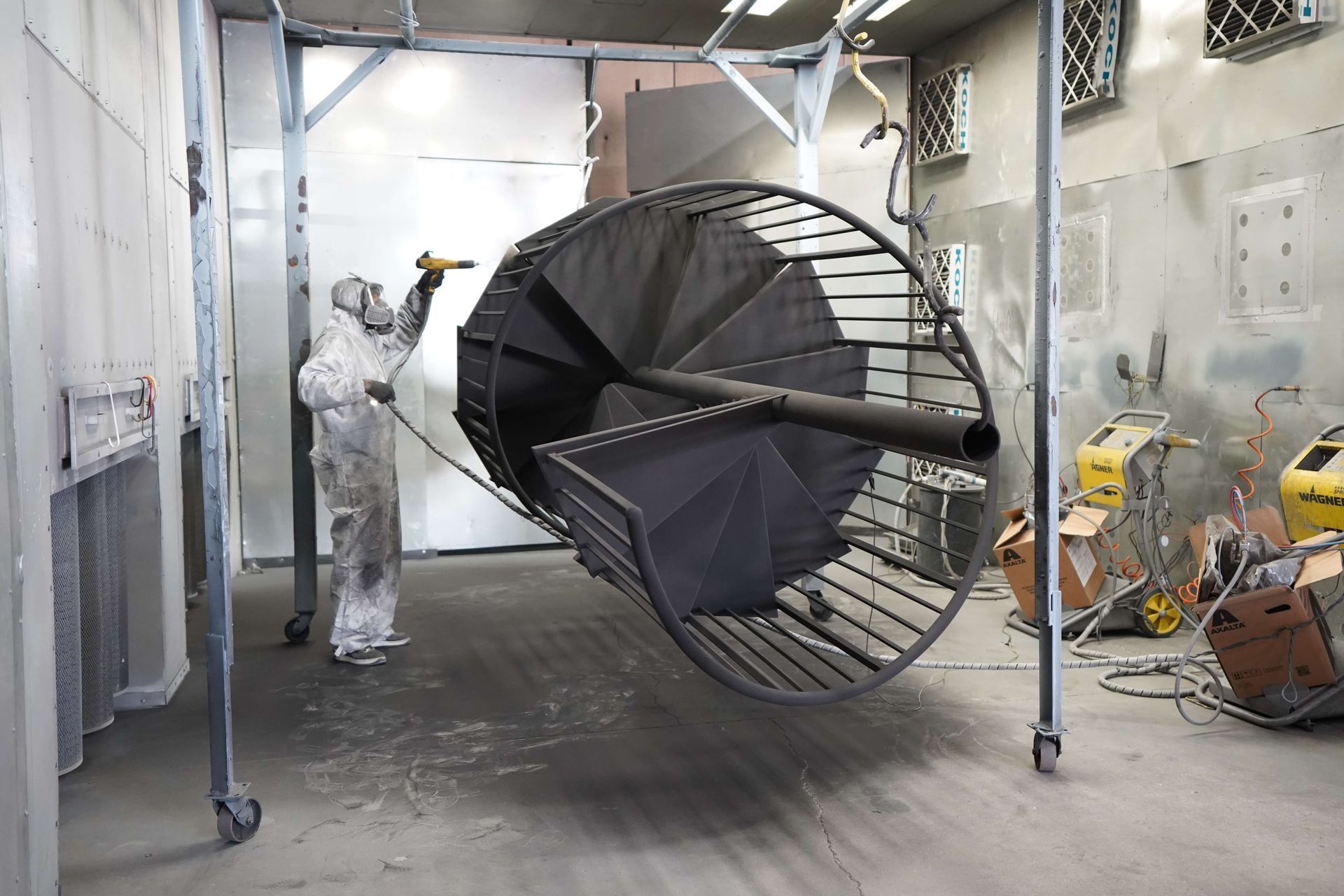 A man is painting a spiral staircase in a room
