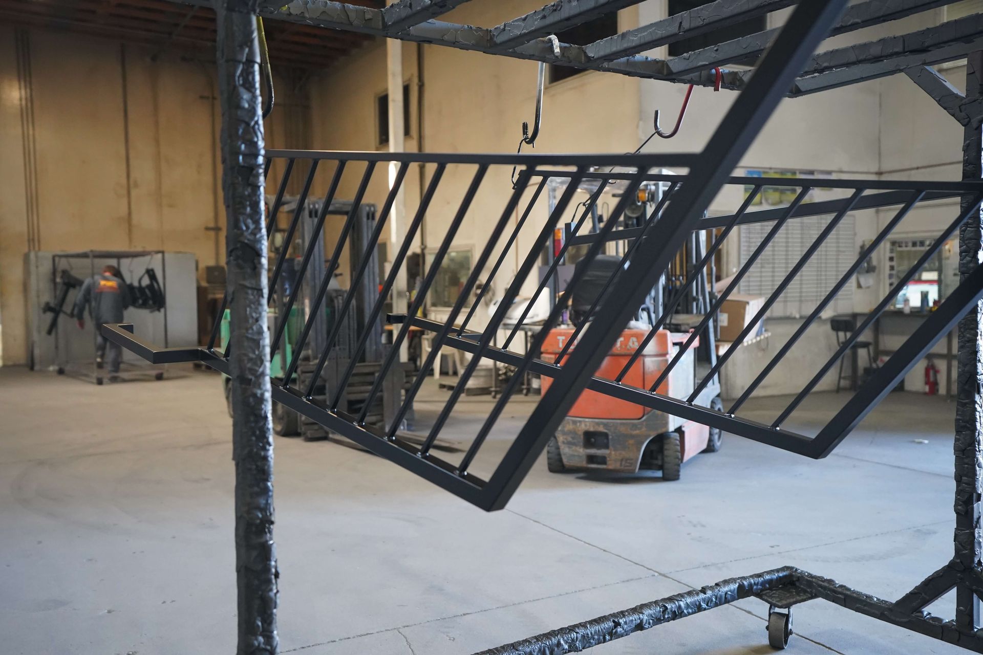A forklift is moving a metal structure in a warehouse.