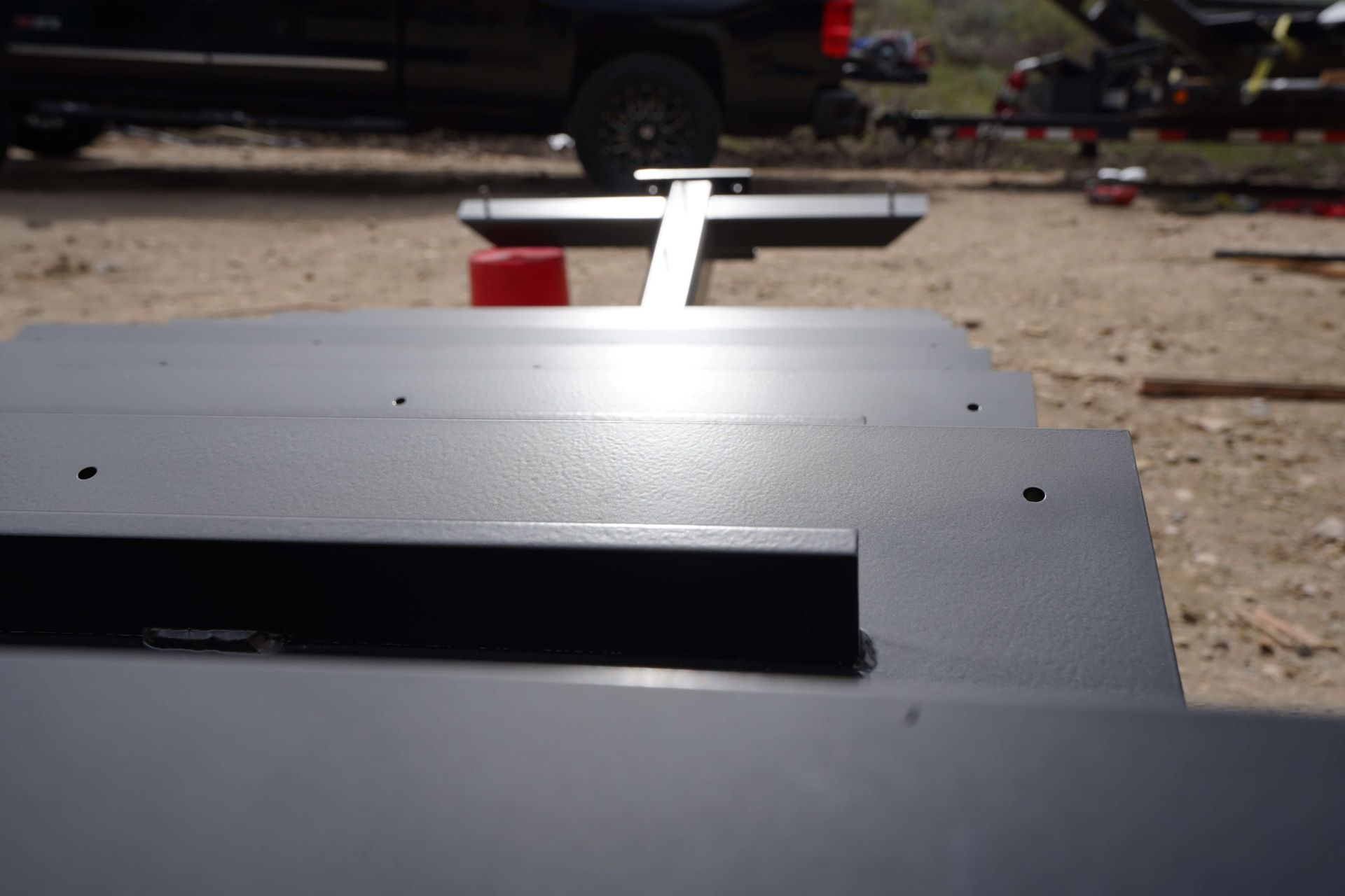 Close-up of a gray metal surface with a black slot, outdoors on a gravel driveway.