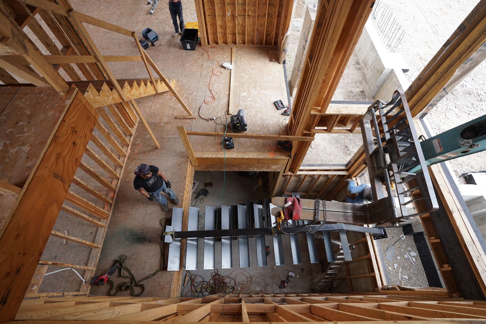 Overhead view of people assembling a wooden staircase in a large unfinished interior