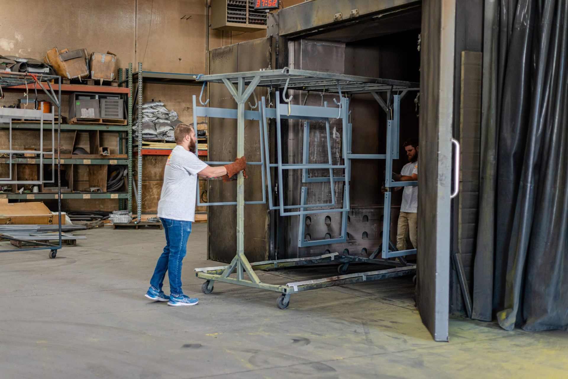 A man is pushing a cart with a metal structure in a warehouse.