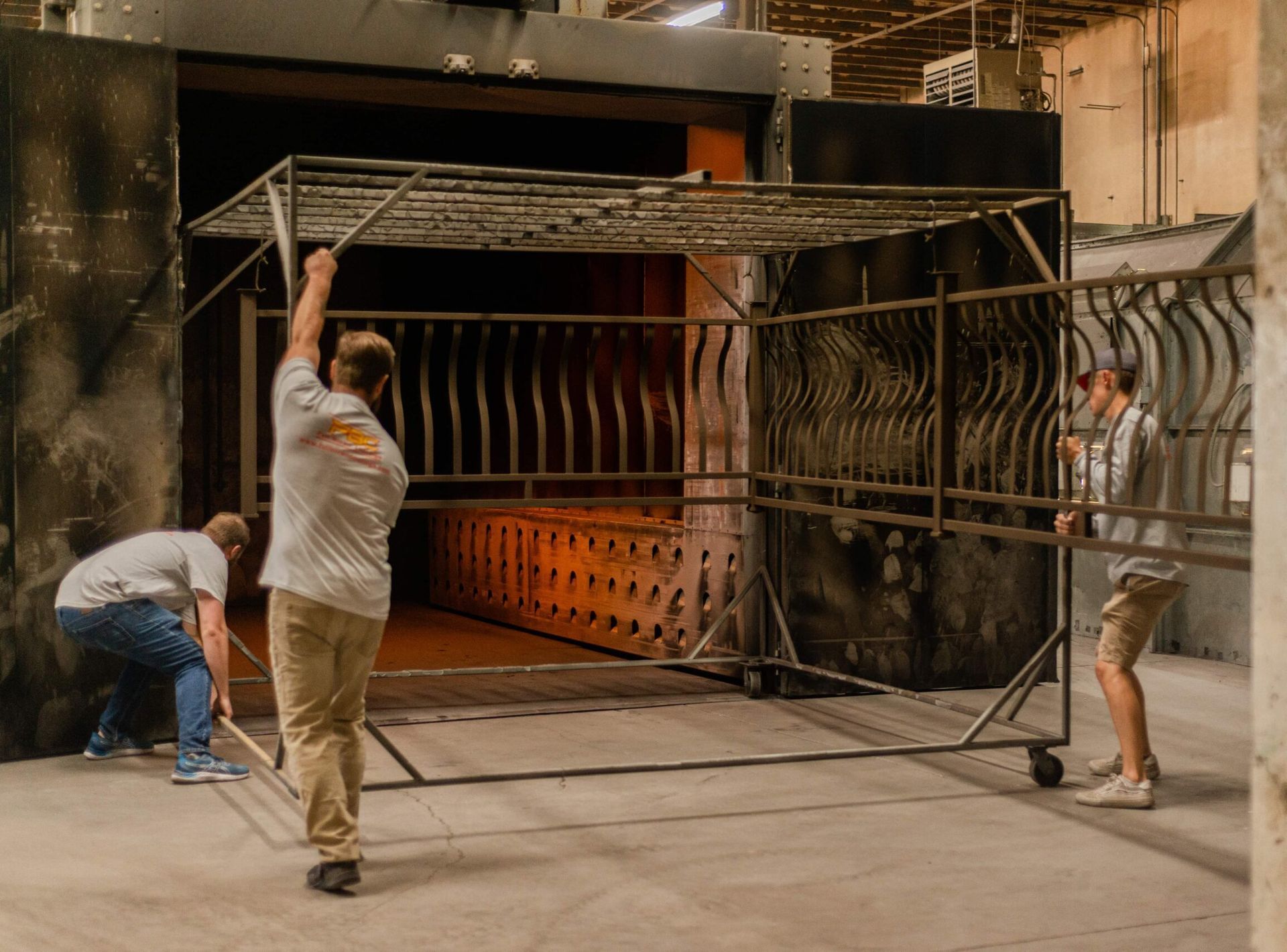 A group of men are working on a metal structure in a factory.