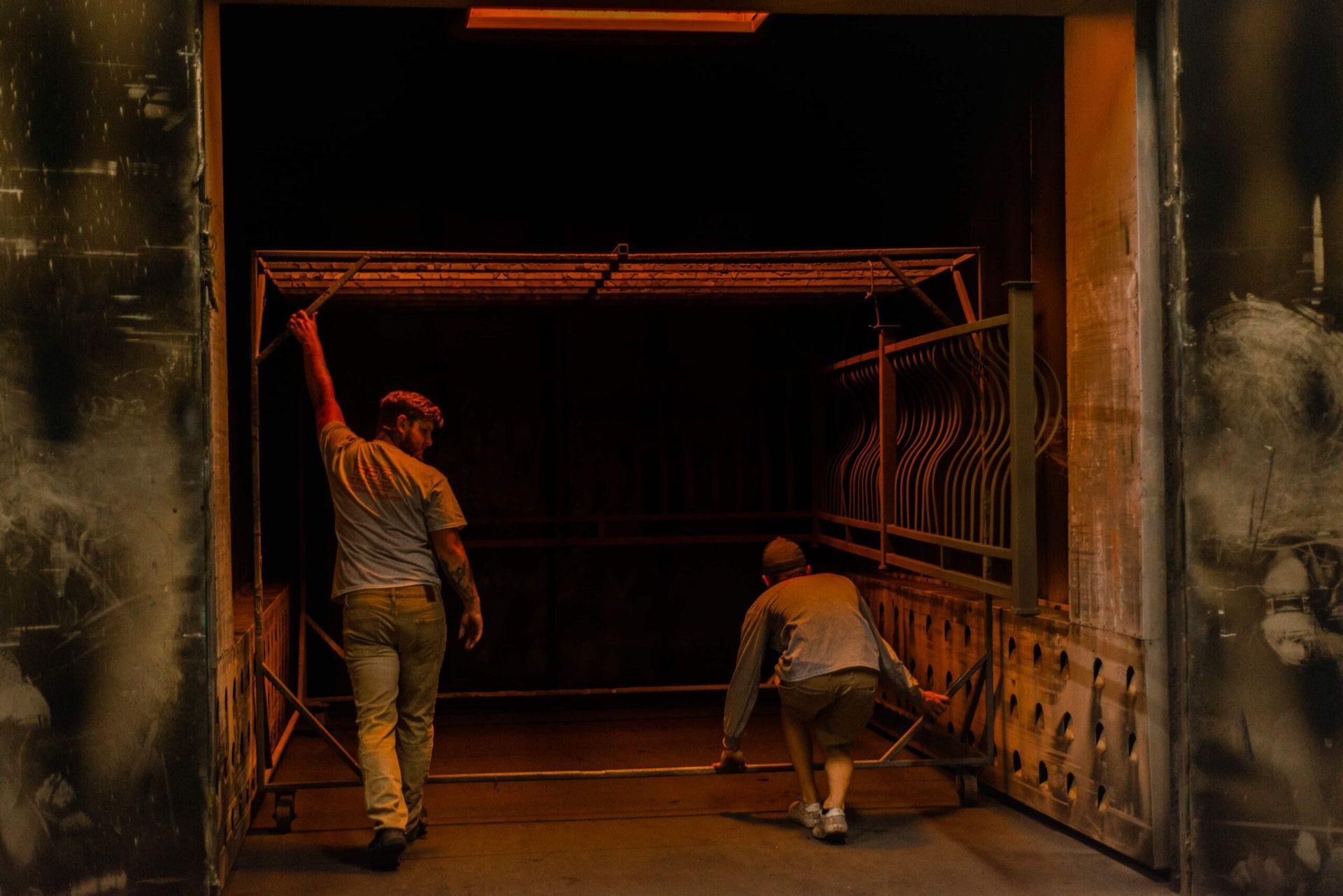 Two men are walking through a dark tunnel.