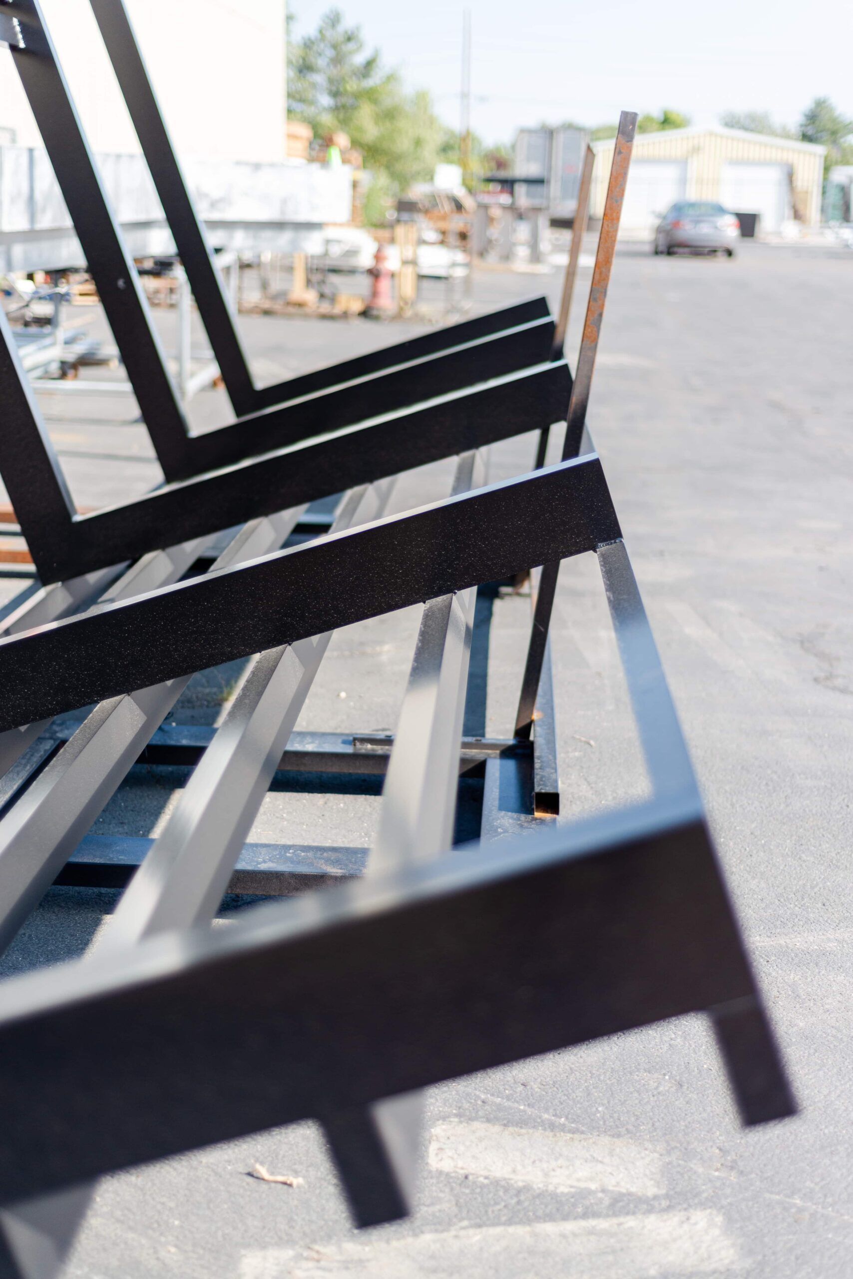 A row of metal frames are stacked on top of each other in a parking lot.