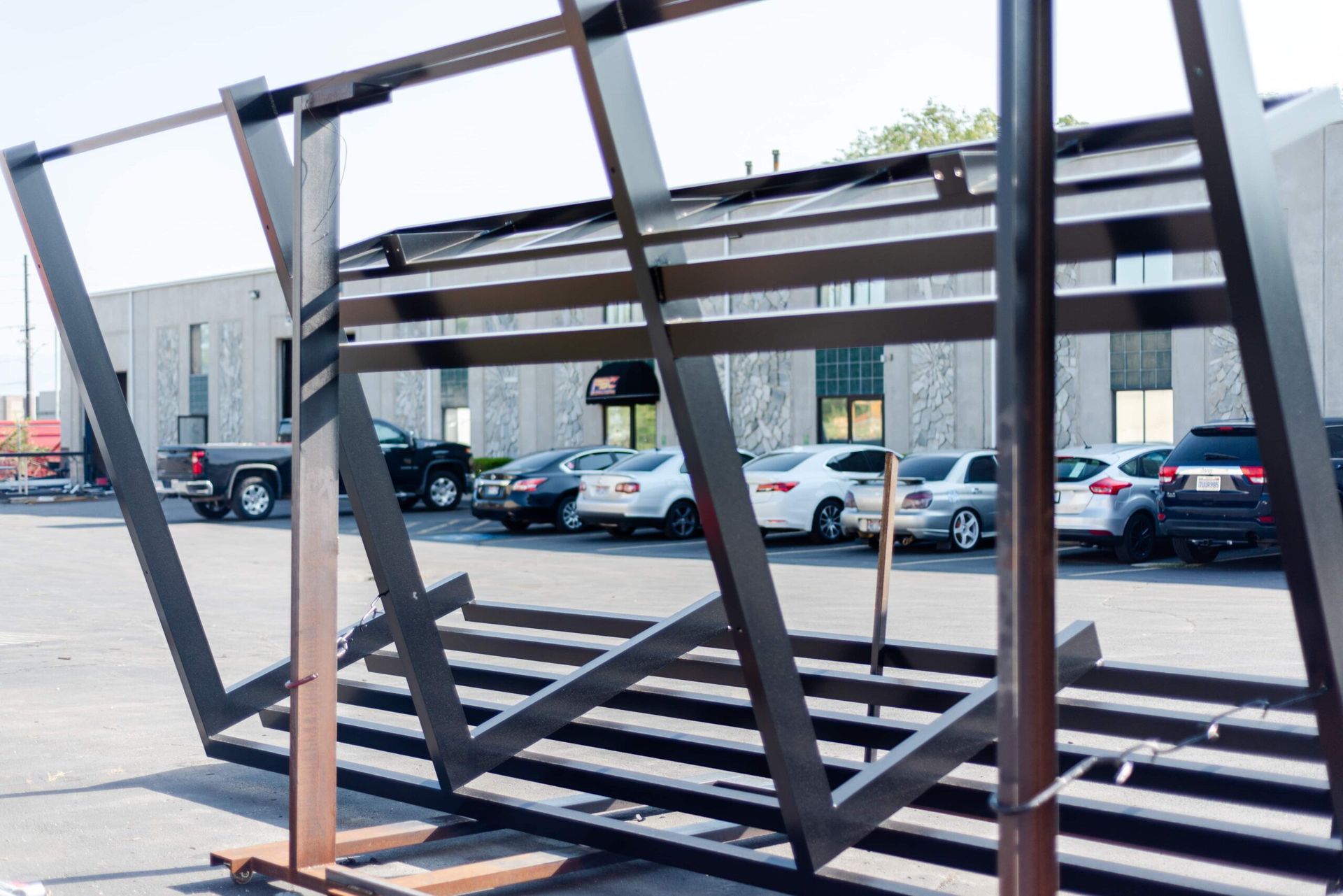 A large metal structure is sitting in a parking lot in front of a building.