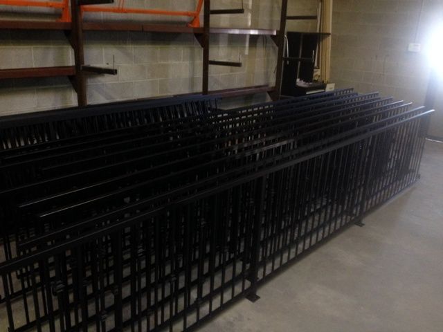 A bunch of black metal fences are stacked on top of each other in a room.