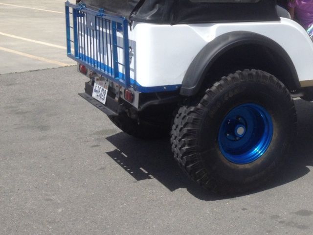 A white jeep with blue wheels is parked in a parking lot