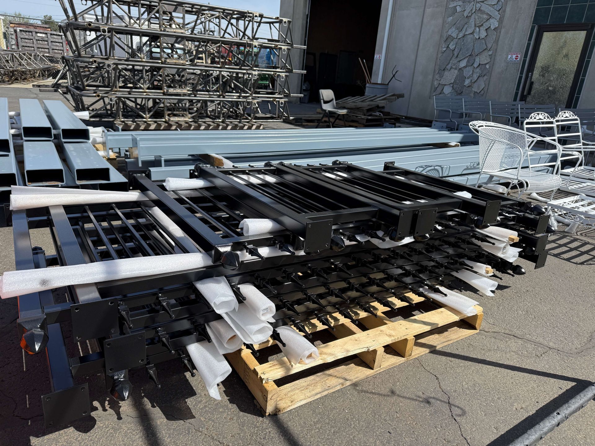 A bunch of powder coated metal pieces are stacked on top of each other on a wooden pallet.