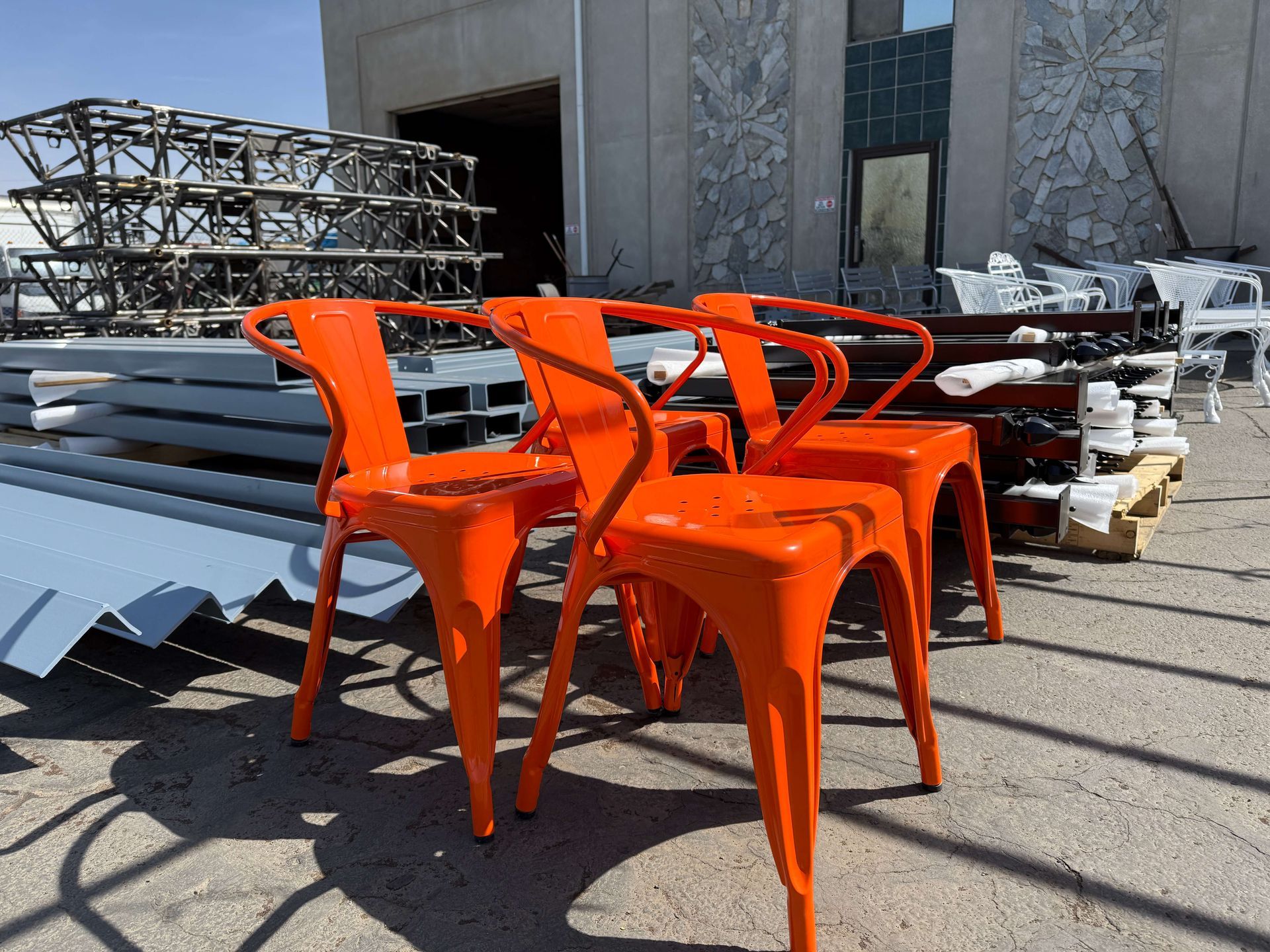 Four powder coated orange chairs are sitting in front of a building