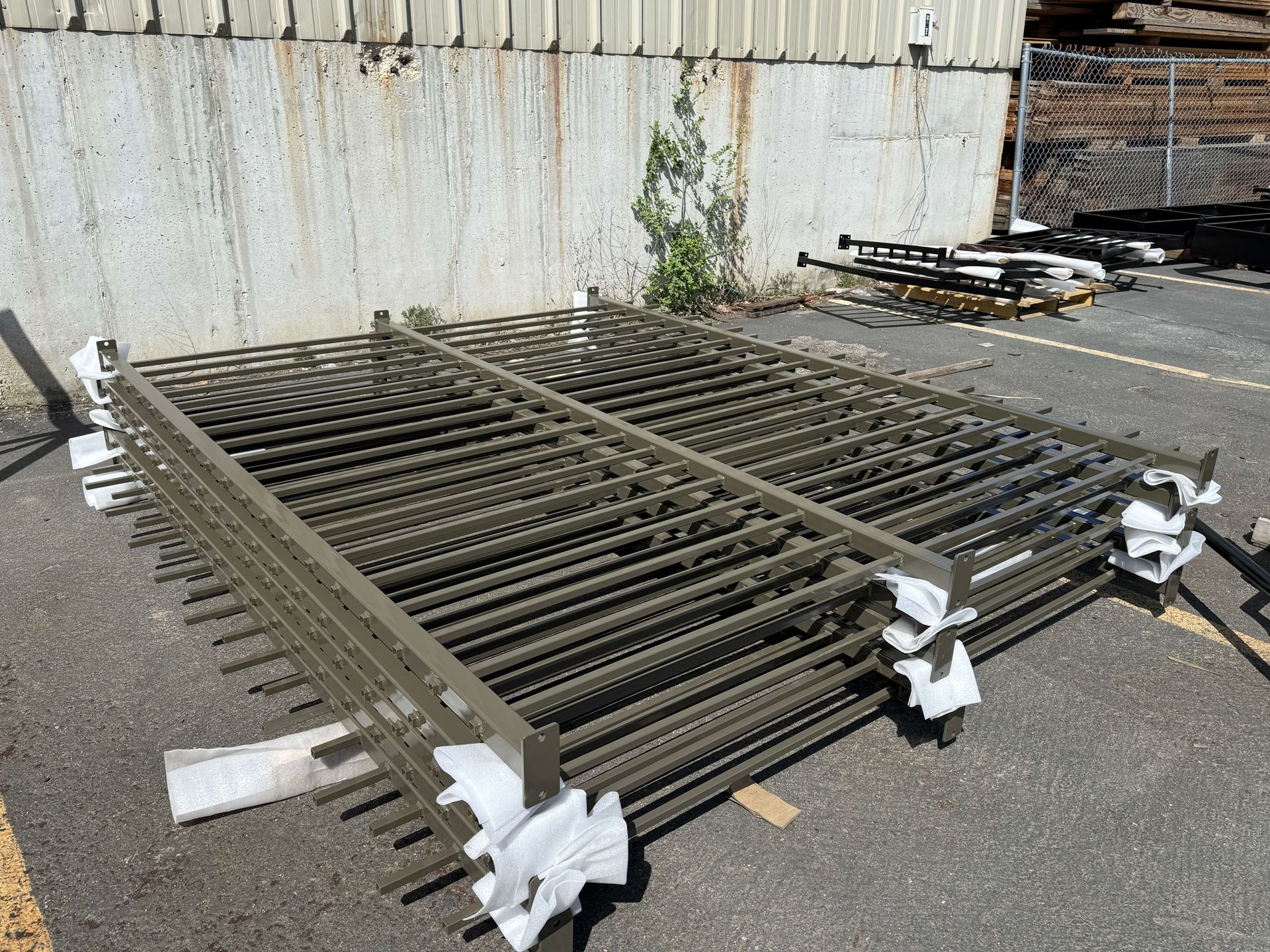 A large sand blasted metal fence is sitting on the ground in a parking lot.